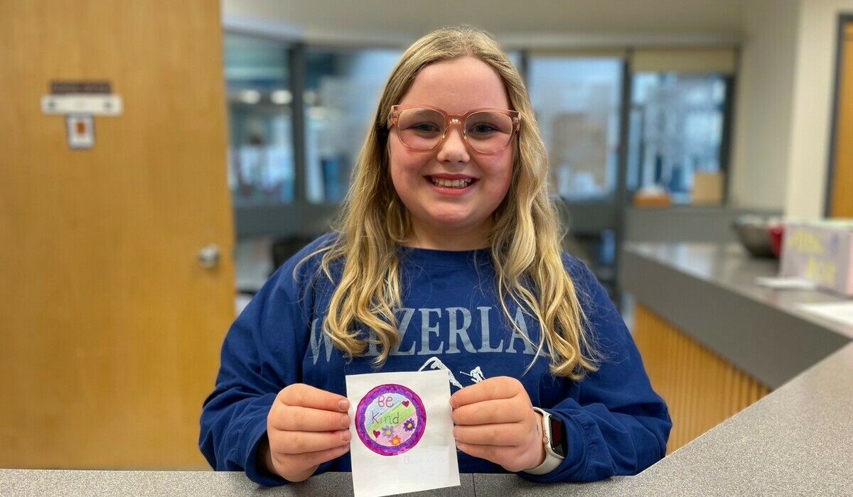 Cutest student all smiles holding up a kindness matters button she designed